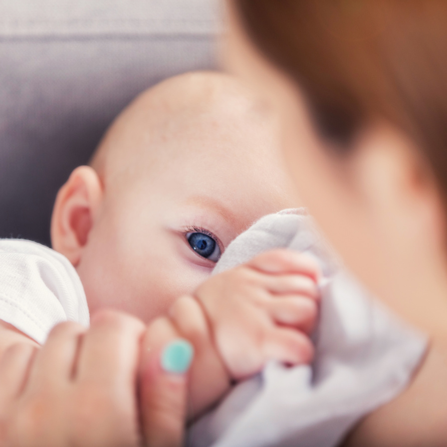 Mom breastfeeds adorable blue-eyed baby